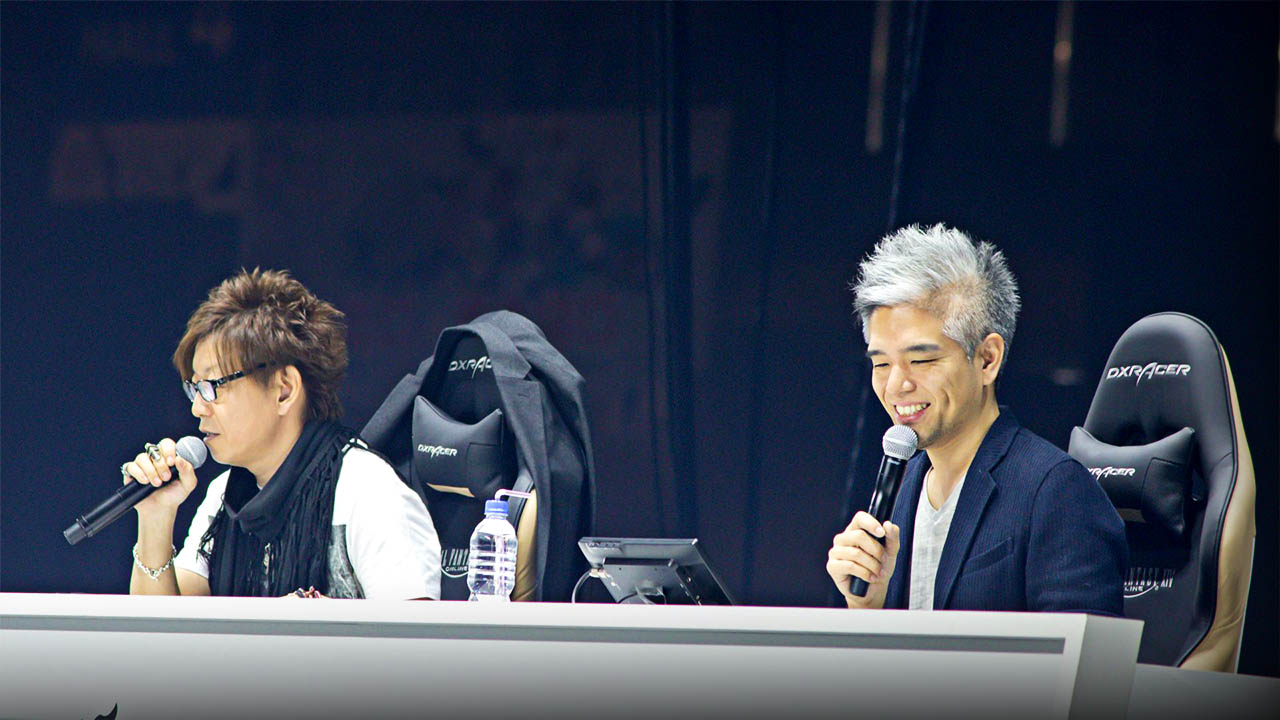 Naoki Yoshida and Toshio Murouchi seated side by side speaking into microphones.